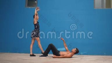 舞蹈伙伴展示感官舞蹈模式与杂技在蓝色背景下缓慢运动。 户外舞蹈